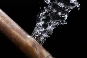 Burst Pipe With Leaking Water On Black Background